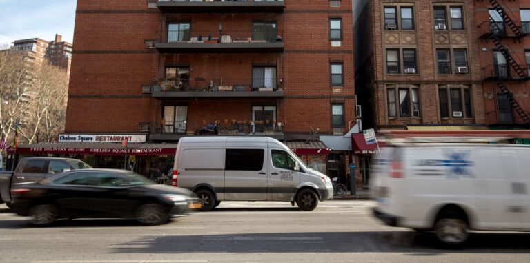 Van in city captured in motion in front of a red building